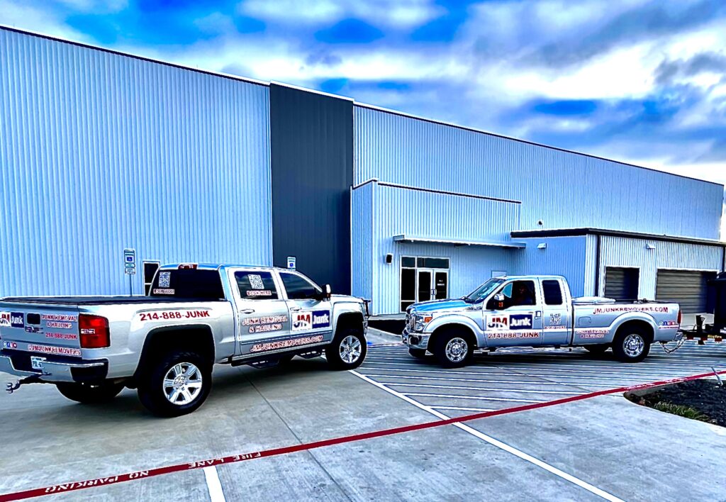 JM Junk Remover branded trucks in front of a commercial warehouse.